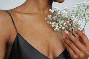 Close-up of an elegant woman in a black dress holding white baby's breath flowers.